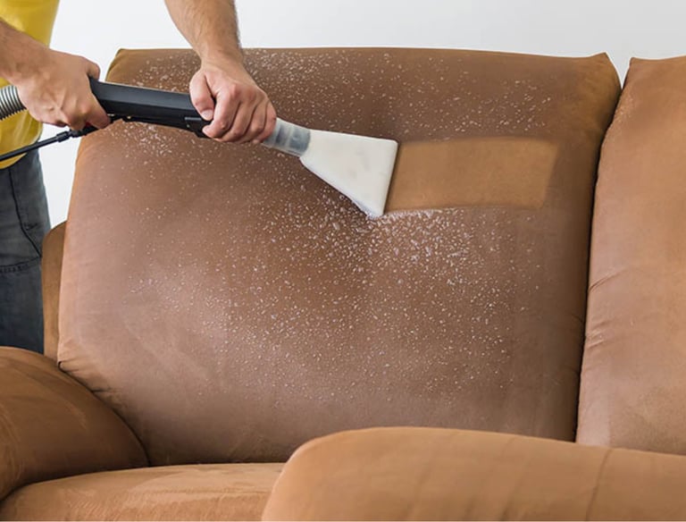 a man cleaning a couch with a vacuum