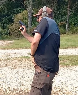 Man retrieving concealed magazine to reload defensive firearm.