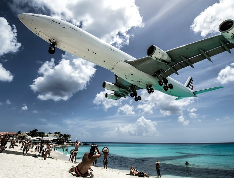An airplane descending to land over a sandy beach