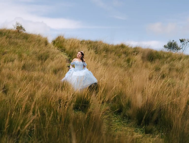 Fotografía de quinceañera con vestido celeste de princesa caminando por el prado amarillo en Quito