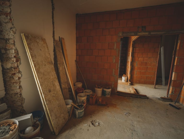 Interior room under construction with red brick walls, concrete floors, and building materials.