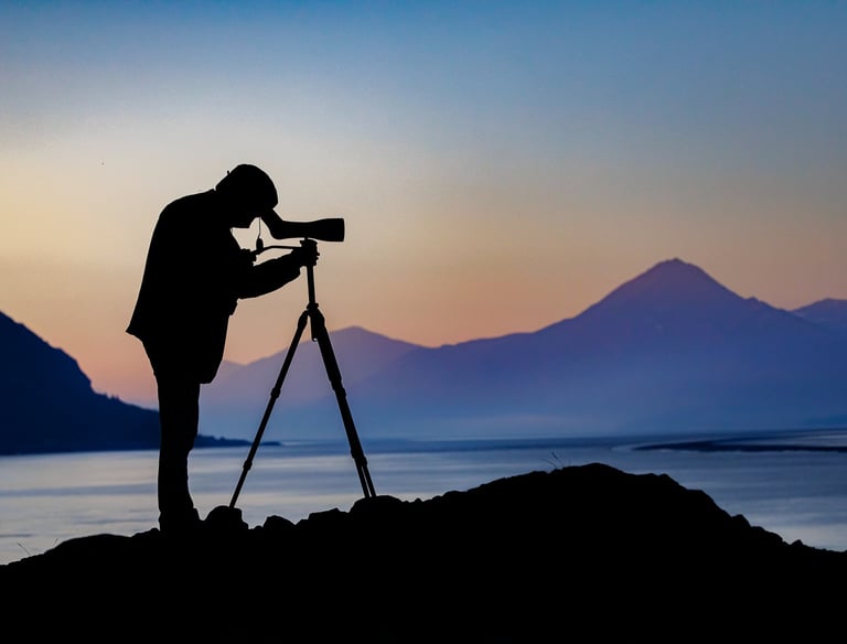 a man standing on a rock with a camera and a tripod