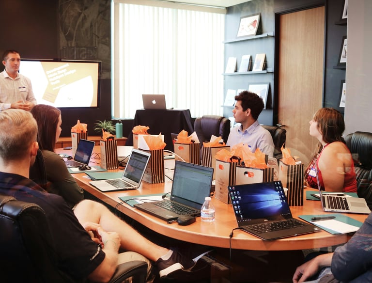 a group of people sitting around a table with laptops