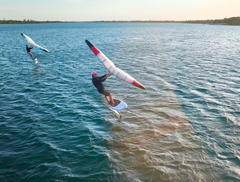 Saulėlydis Svencelėje su wing foil sportininku virš vandens paviršiaus