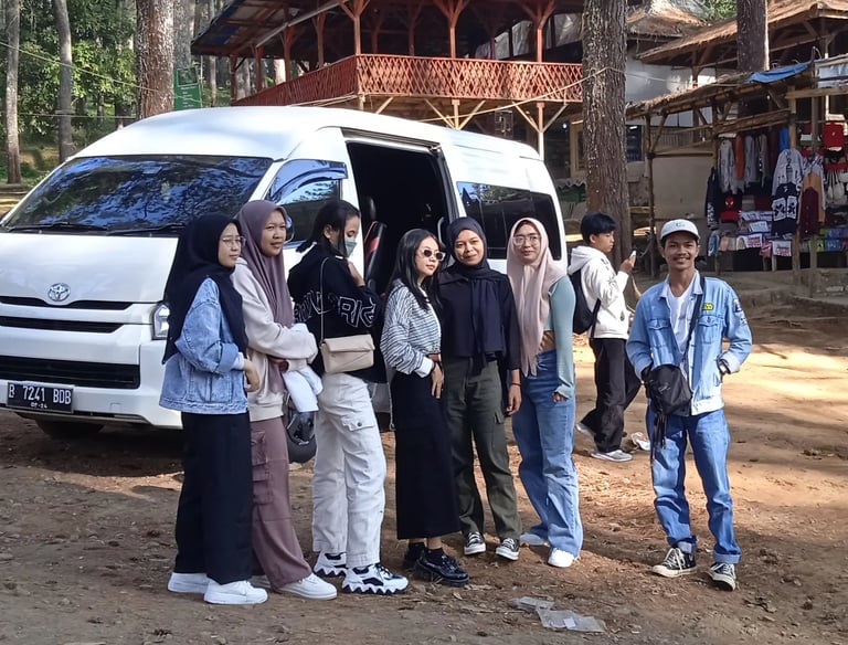 Dua orang pria enam orang perempuan berpose di depan Hiace putih dengan pintu terbuka.