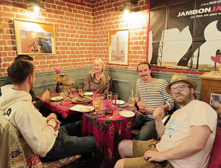 A group of friends enjoying dinner and drinks at a rustic restaurant with red brick walls.