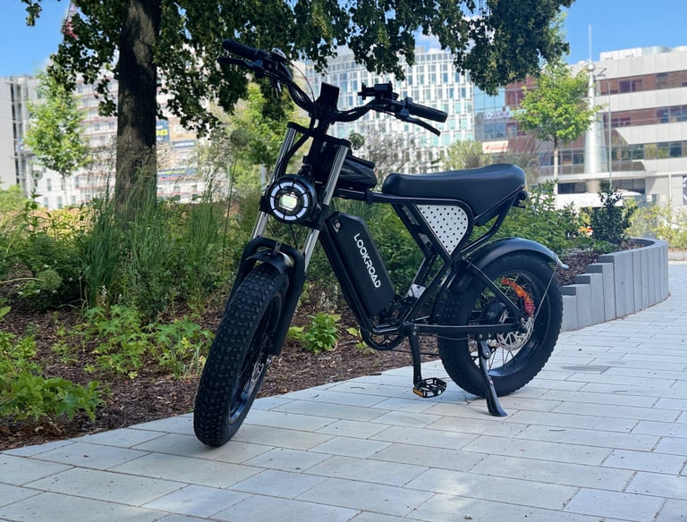 Black Lookroad all-terrain fat tire electric bike parked on a city sidewalk path.