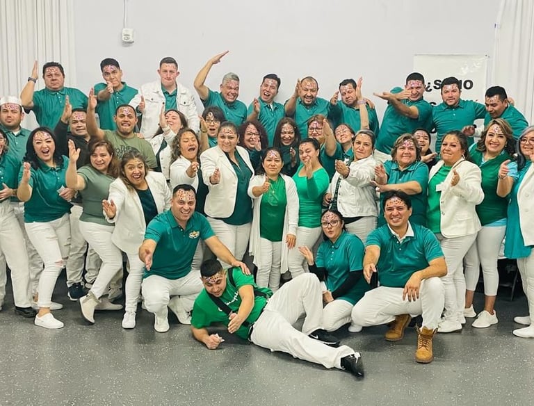 A cheerful group of people in matching teal and white attire posing for a team photo.