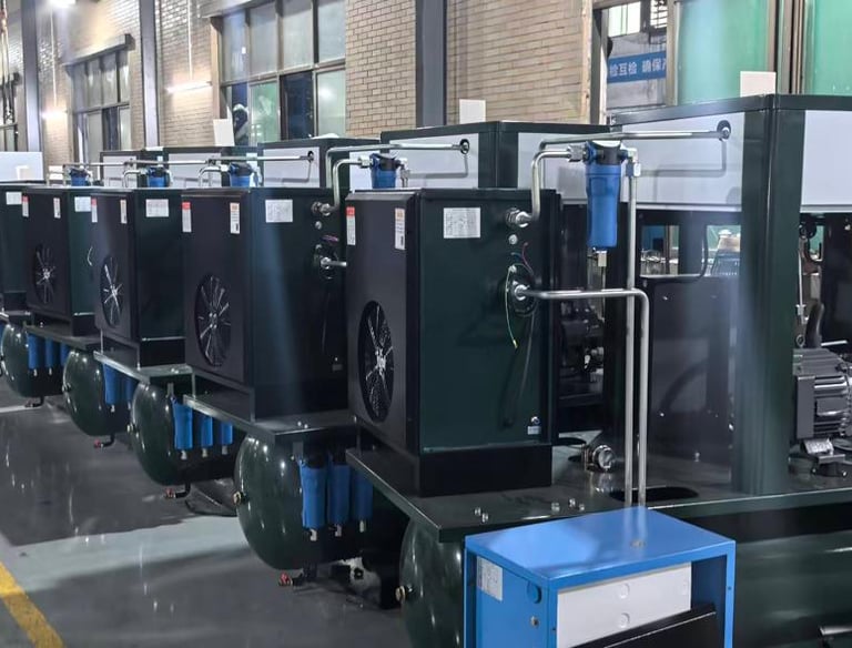 A row of industrial rotary screw air compressors with tanks in a manufacturing facility factory.