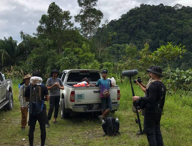 a group of people standing around a truck during documentary shooting