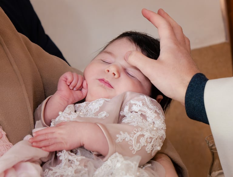 mala beba spava dok ju svećenik blagoslovi