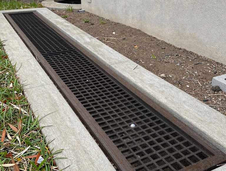 A technician carefully installing a new drain field in a green backyard.