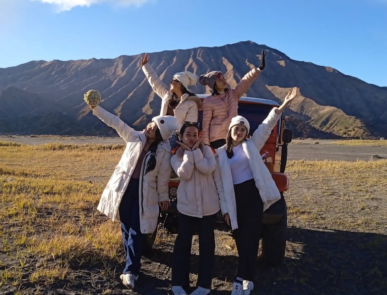foto sekelompok wanita berpose di depan jeep dengan latar belakang gunung bromo