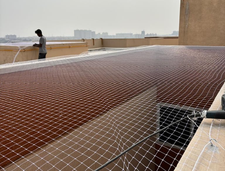 Wide shot of an open balcony area fitted with pigeon safety nets under bright sunlight.