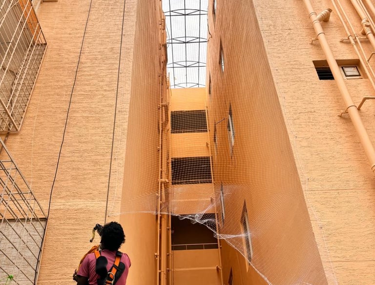 Installation team fitting safety nets around duct areas on an apartment exterior.