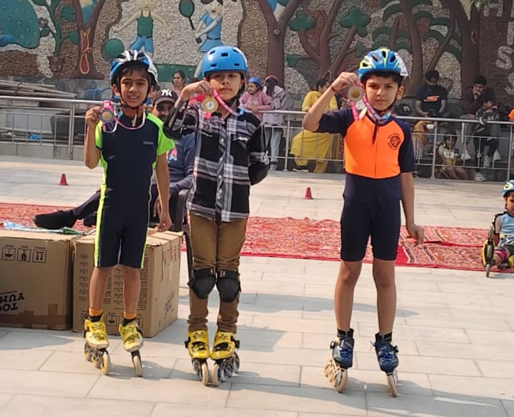 Young children wearing helmets and inline skates proudly display medals after a roller skating competition.