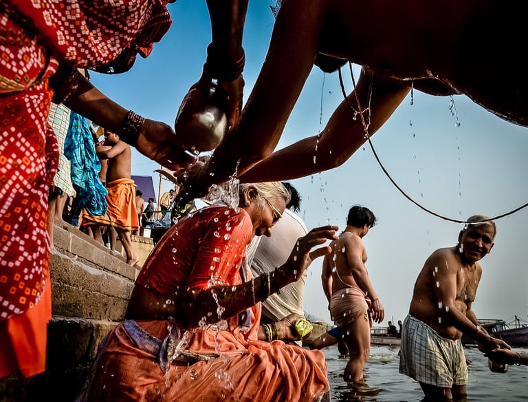An elderly woman gets playful help from her family in ritual with the Ganges River in Varanasi.