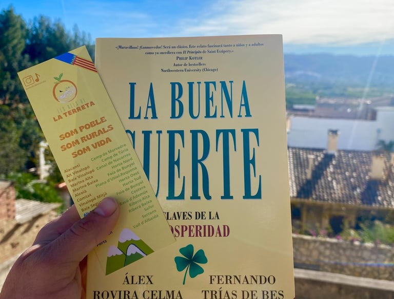Libro La Buena Suerte con marcapáginas de diseño local y paisaje de montaña de fondo
