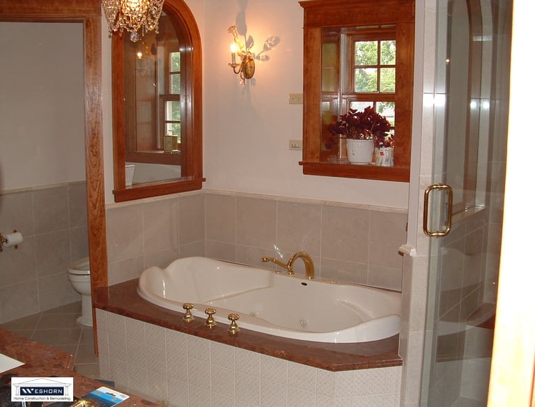 Luxury master bathroom featuring a built-in jetted soaking tub with gold fixtures and elegant wood trim.