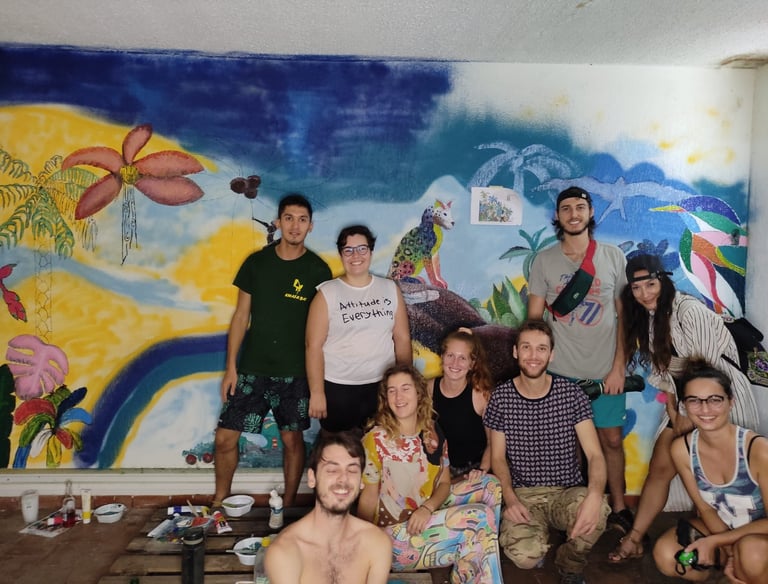 Un groupe de bénévoles de divers horizons pose devant une fresque murale tropicale colorée