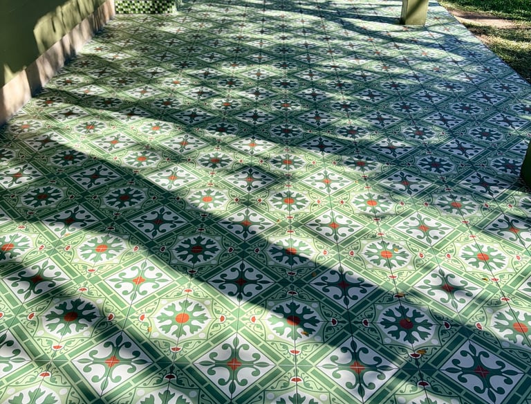Outdoor patio featuring green patterned cement tiles with a vintage floral design in a sunny backyard.