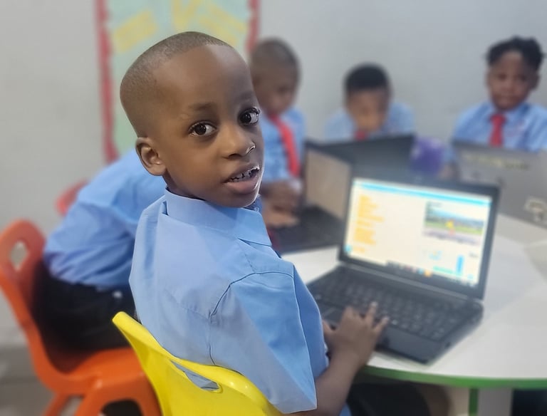A 5 year old boy coding with his classmates in his classroom