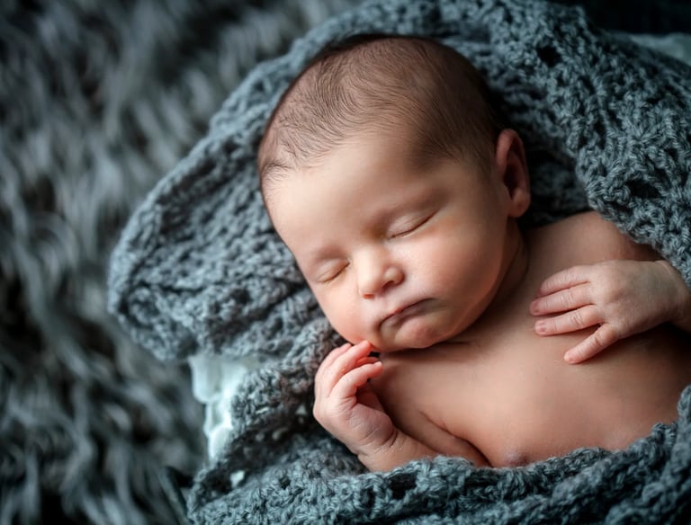 un bébé dort dans un plaid en tricot gris