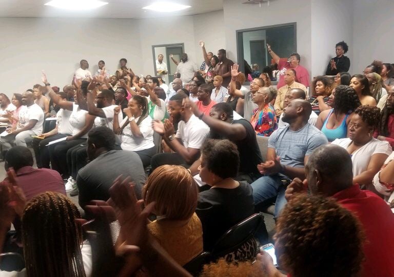 Group of people in an office raising their hands