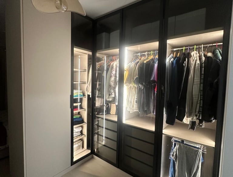 Vestidor moderno con iluminación interior y puertas de vidrio.