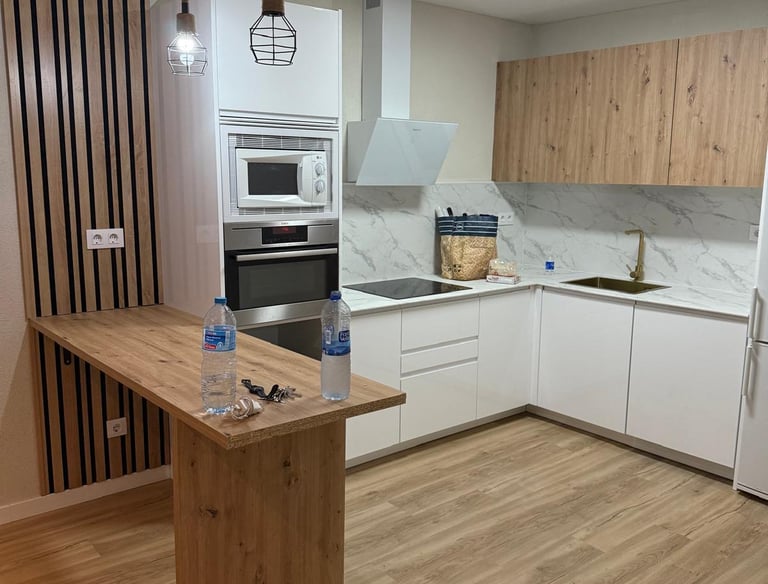 Cocina moderna con barra, muebles de madera y electrodomésticos.