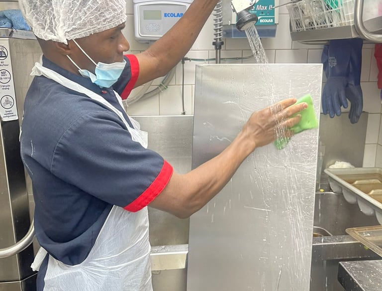 Kitchen steward washing a chiller cover at Upskill Hospitality LLC- Culianry Training School