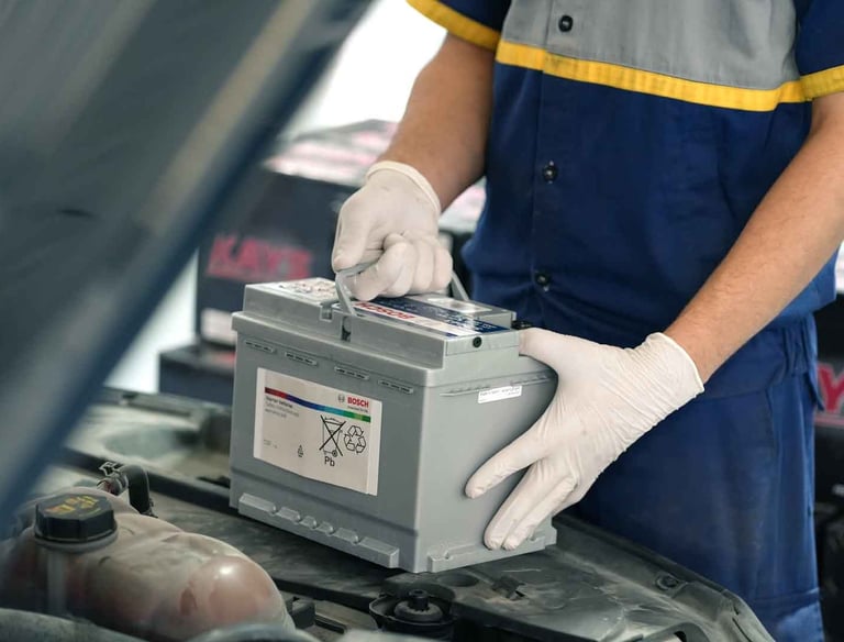 فني يقوم بتركيب بطارية سيارة جديدة في الكويت