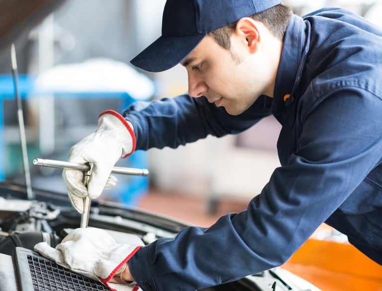 فني يقوم بتركيب بطارية سيارة جديدة في الكويت