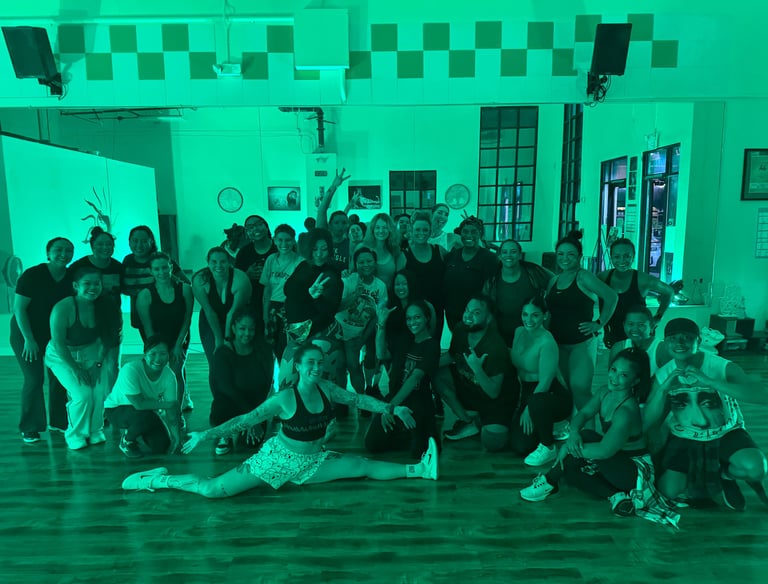 A group of dancers posing in front of a mirror with smiling faces.