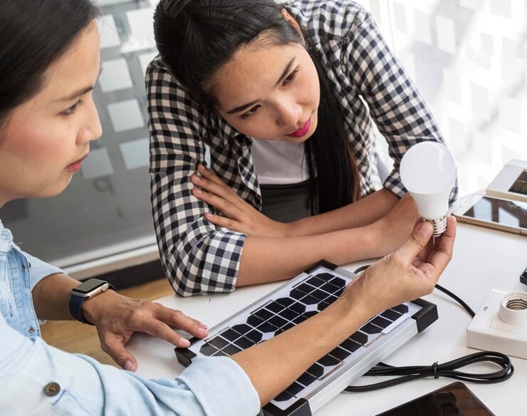 Deux femmes discutant d'une ampoule LED avec un clavier en braille sur la table.