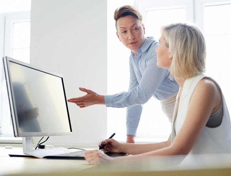 Un professionnel en chemise bleue montre des informations sur un écran d'ordinateur à une femme blo