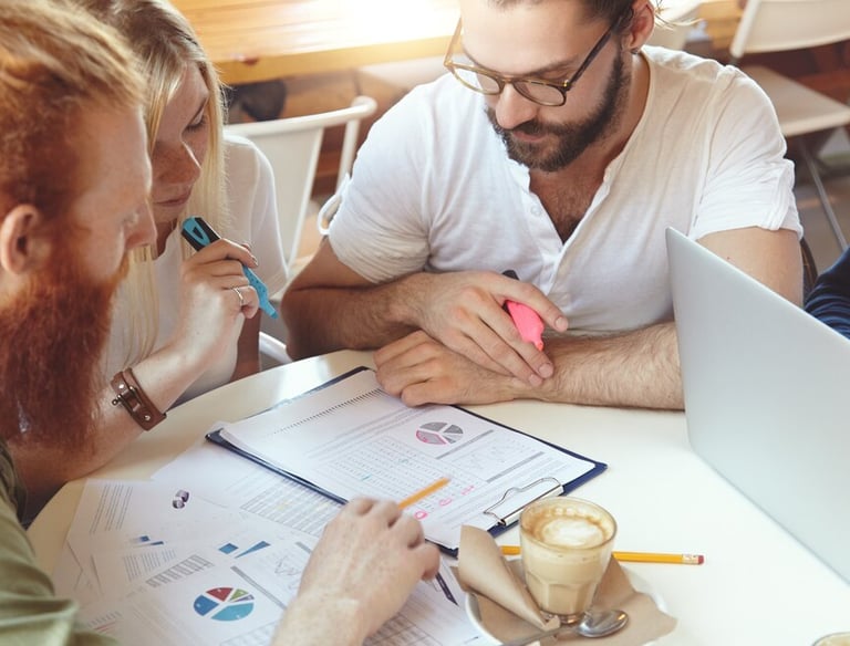 Trois personnes assises à une table, concentrées sur un document pendant une session de formation.