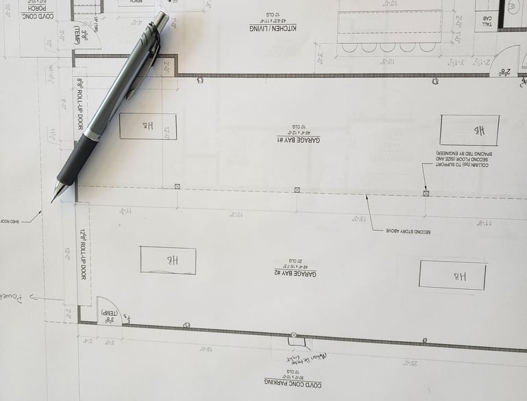 Architectural floor plan blueprints with a mechanical pencil for residential garage and kitchen design.