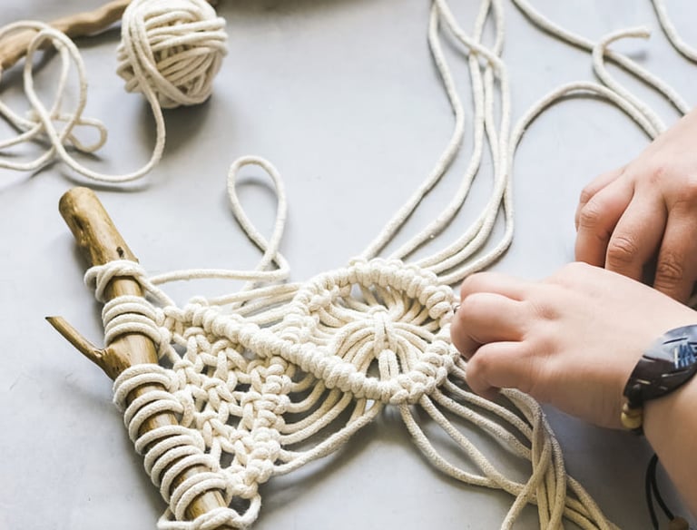 mujer realizando macrame decorativo sobre una rama de madera
