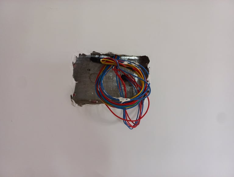 Exposed colorful electrical wires in a metal wall junction box during home renovation.