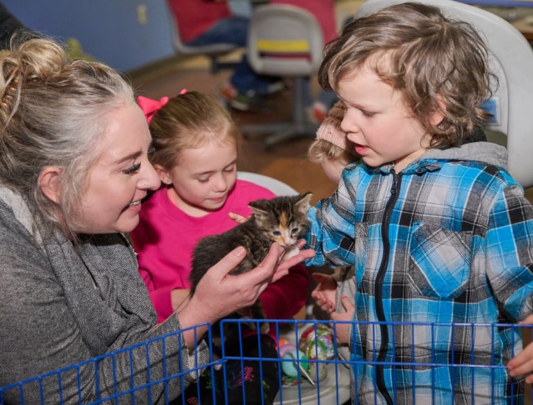 a woman holding on her hand and a boy petting it