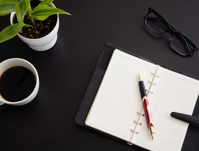 a notebook with a pen and a cup of coffee
