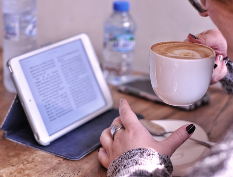 a woman holding a cup of coffee and a tablet