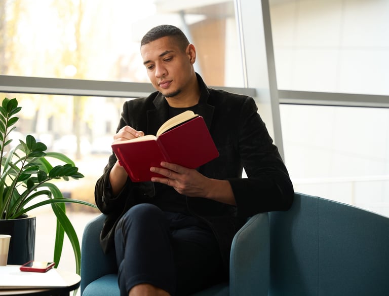 a man sitting on a couch reading a book