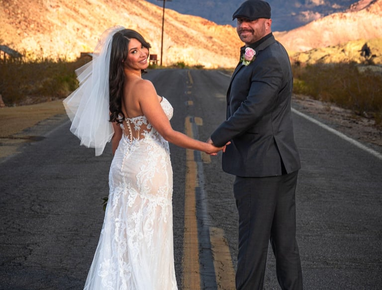 a bride and groom holding hands on a road