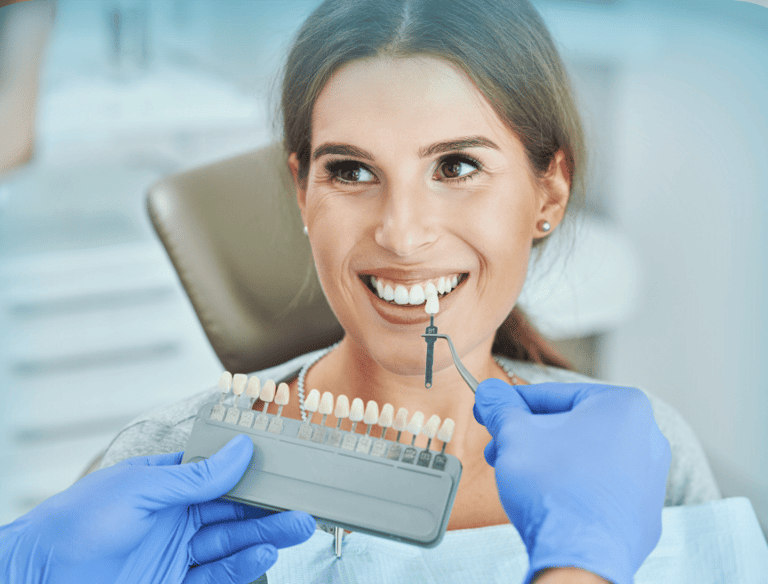 Dentista comparando el color de los dientes de una paciente con una guía de tonos para carillas