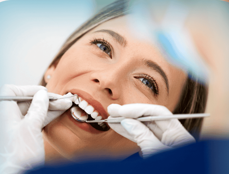 Una mujer joven sonriendo durante un chequeo dental, con un dentista examinando sus dientes 