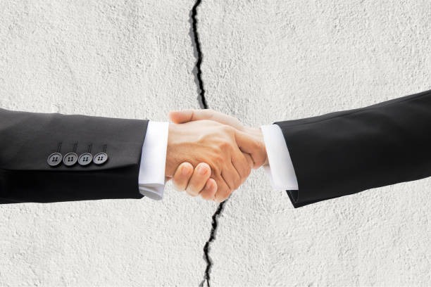 deux hommes en train de se serer la main avec en fond un mur qui se fissure