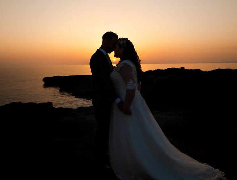 una sposa e uno sposo che si baciano davanti al tramonto