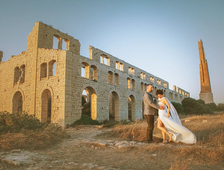 una sposa e uno sposo in piedi davanti a un edificio in pietra in Sicilia